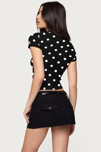 Detail of the black polka dot top paired with a belted skirt and golden buttons