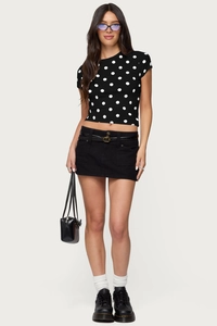 Detail of a black polka dot crop top paired with a denim mini skirt and leather handbag