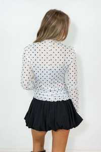 Detail of sheer polka dot mesh top with ruffled high neck and back model view