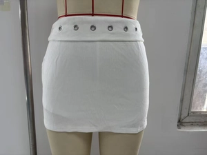 Détail d'une mini-jupe blanche en maille côtelée avec œillets argentés et coupe ajustée
