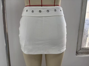 Détail de la mini-jupe blanche en maille côtelée avec œillets métalliques à la taille