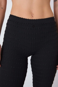 Détail du pantalon à carreaux taille haute avec tissu gaufré et bouton décoratif chic