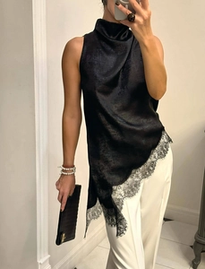 Detail of elegant black satin halter top with lace patchwork and asymmetric hemline style