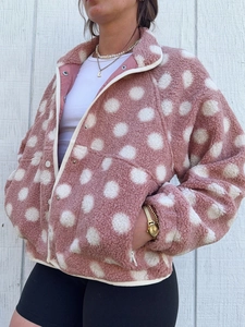 Detail of pink fleece jacket showing soft texture, white polka dots and stand collar