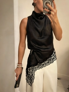 Detail of elegant black satin halter top with asymmetric lace trim and silk finish