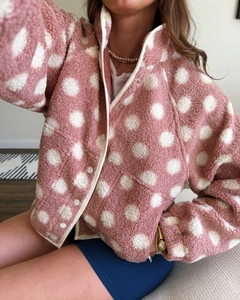 Detail of pink polka dot fleece jacket featuring stand collar and button-up closure