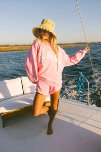 Detail of pink oversized hoodie with letter print and striped bucket hat on a yacht
