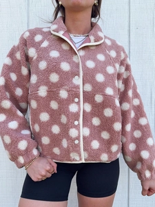 Detailed texture of mauve polka dot fleece jacket with stand collar and white buttons