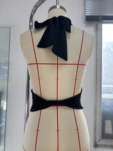 Detailed back view of a black halter top featuring a large bow tie and twisted straps