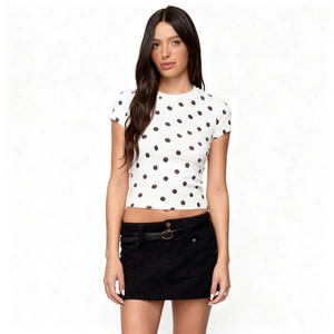 Detail of white short sleeve top with polka dot pattern and slim fit design on a model