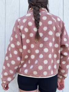 Detail view of the plush pink sherpa fleece jacket with large white polka dots on the back