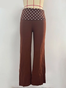 Detail of high-waisted wide-leg trousers in brown with a white polka dot waistband design