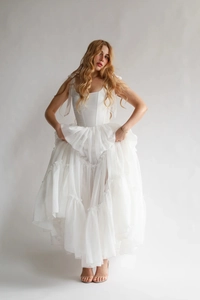 Détail d'une robe corset blanche avec volants superposés et nœuds en ruban aux épaules