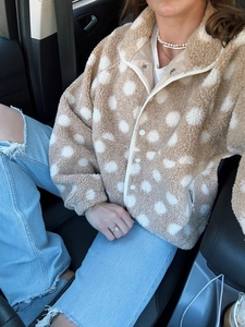 Detailed macro view of the cream fleece jacket featuring white polka dots and round buttons