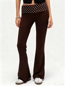 Detail of slim fit dark brown flare pants with retro polka dot waistband and stretchy fabric