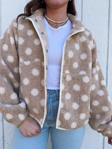 Detail of polka dot fleece jacket featuring silver snap buttons and white trim edges