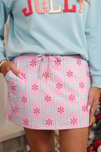 Close-up of pink mini skirt with candy swirl patterns and JOLLY sequin embroidery