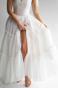 Vue détaillée d'une robe plissée blanche multicouche avec corsage ajusté et ourlet à volants