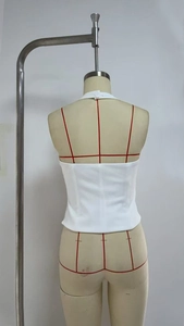Detail view of white halter top back with double button closure on a dress form