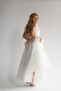Détails de la robe blanche à volants avec couches transparentes et nœuds aux épaules