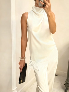 Detail of white satin sleeveless top featuring a high neck and floral lace hem trim