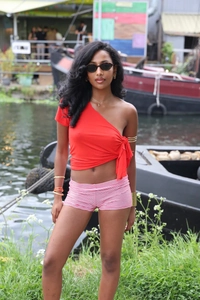 Detail of red one-shoulder top with side bow tie and striped high-waisted shorts