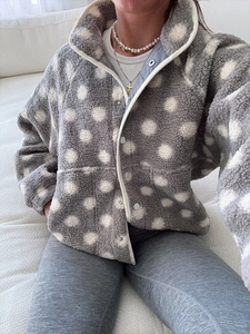 Detail of grey fleece jacket with white polka dots, high collar and metal snap buttons