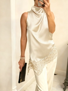 Detail of champagne satin halter top featuring delicate lace trim and asymmetrical hem