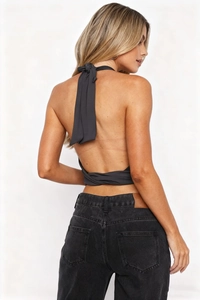 Detail of the black backless halter top with tie-up straps and matching denim jeans
