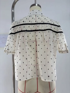 Détail du dos d'un chemisier à pois et cœurs avec rubans noirs et finitions plissées