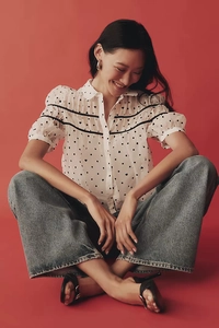 Détail de la blouse blanche à manches bouffantes avec motif cœur et rubans