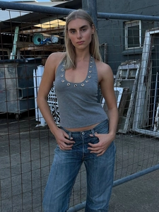 Detail of grey halter top featuring decorative metal grommets around the neckline