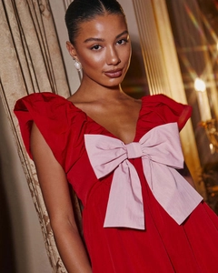 Detail of red sleeveless party dress featuring a large pink bow on a deep V-neckline
