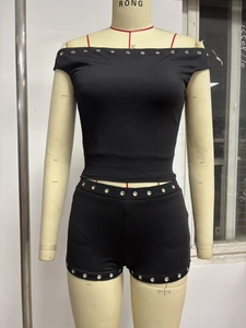 Close-up of black ribbed knit off-shoulder top and shorts with silver metal eyelets