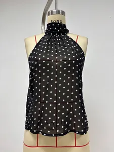 Detailed close-up of a black polka dot halter neck top with soft pleated collar details
