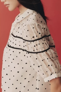 Détail des manches bouffantes avec ruban noir et imprimé cœurs à pois sur chemise