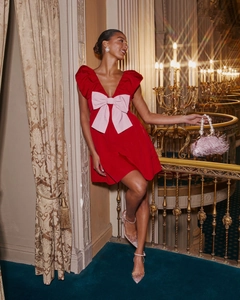 Detail of red V-neck party dress featuring a large pink bow and luxurious satin texture