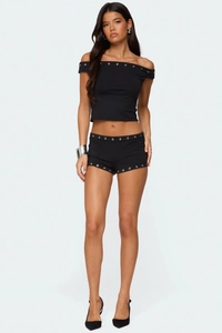 Detail of silver grommets and rivet design on black off-shoulder crop top and shorts set