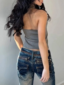 Detail of slim fit halter top with denim jeans featuring vintage wash and zipper pockets