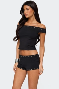 Detail of silver metal eyelets on black off-shoulder crop top and matching tight shorts set