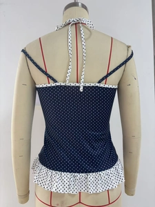 Detailed back view of a blue polka dot halter top with ruffle hem on a mannequin