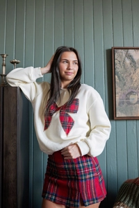 Detail of cream sweatshirt with large red plaid bow and matching tartan mini skirt
