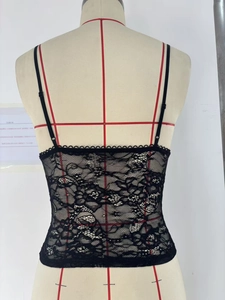 Detail of floral lace mesh and adjustable spaghetti straps on a slim black camisole