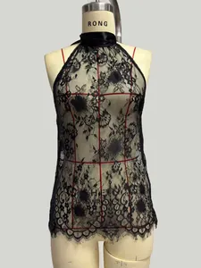 Detailed close-up of delicate floral lace fabric and eyelash trim on the black halter top