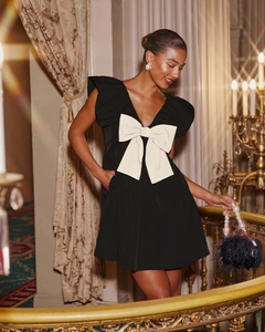 Close-up of elegant V-neck dress featuring a large cream bow and ruffled cuffs detail