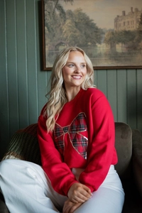 Detail view of a red sweatshirt featuring a festive plaid bow with gold sequin embroidery