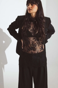 Detail of floral lace texture on a black halter top paired with a tailored blazer