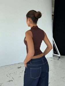 Detail der eleganten Spitzenkante an einem dunkelbraunen, ärmellosen Damen-Top