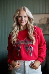 Detail of red long sleeve sweatshirt featuring a large plaid bow with gold accents