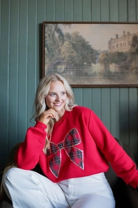 Detail of red crewneck sweatshirt featuring a large plaid bow with sequined edges
